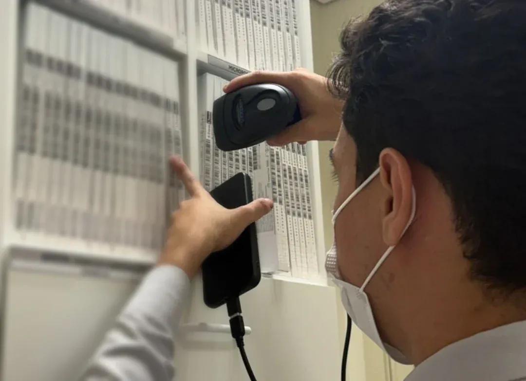 Auditor da CPL bipando caixas de OPME na prateleira do hospital